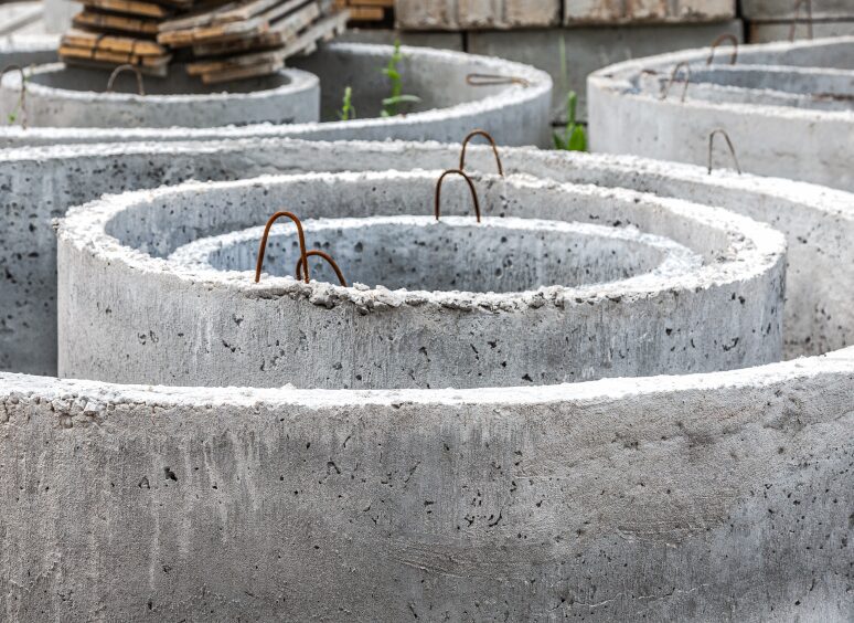 Stacked concrete rings with metal hooks in an outdoor storage area.