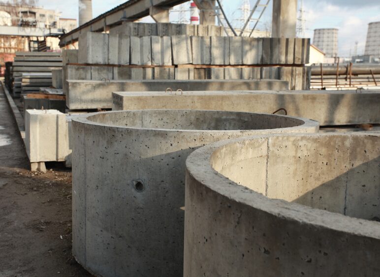 Large cylindrical concrete pipes stacked outdoors at a construction site.